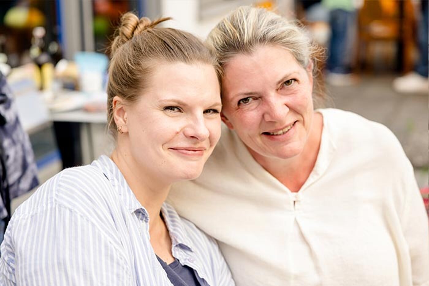 Zwei Frauen sind dicht beieinander und lächeln in die Kamera.